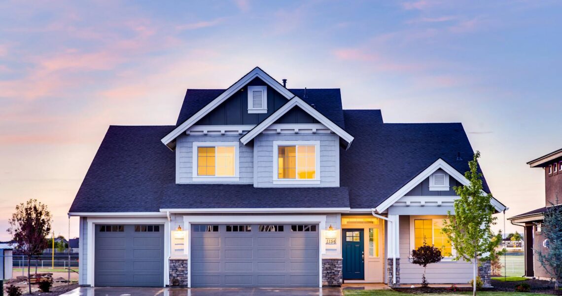 Belle maison à étage avec fenêtres et garage illuminés au crépuscule.