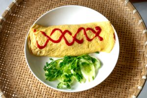 une assiette blanche surmontée d'une omelette recouverte de sauce