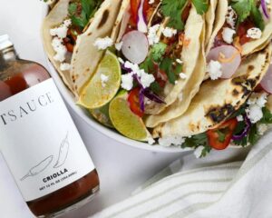 une assiette de tacos à côté d'une bouteille de sauce